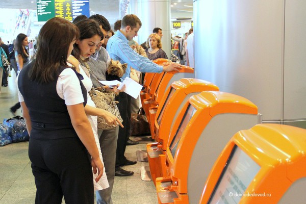Консультант помогает пассажирам зарегистрирваться на рейс