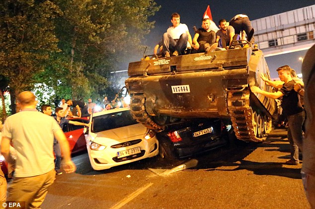 People on a tank run over cars on a road in Istanbul, Turkey on Saturday. Turkish Prime Minister Yildirim reportedly said that the Turkish military was involved in an attempted coup d