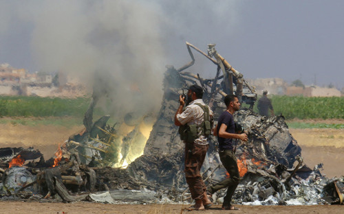 Мужчины осматривают обломки российского вертолета, который&nbsp;был сбит повстанцами в&nbsp;сирийской провинции Идлиб